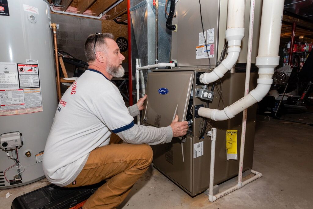 An HVAC technician from Wyles Heating & Air Conditioning Inc. servicing an indoor furnace unit in North Canton, OH.