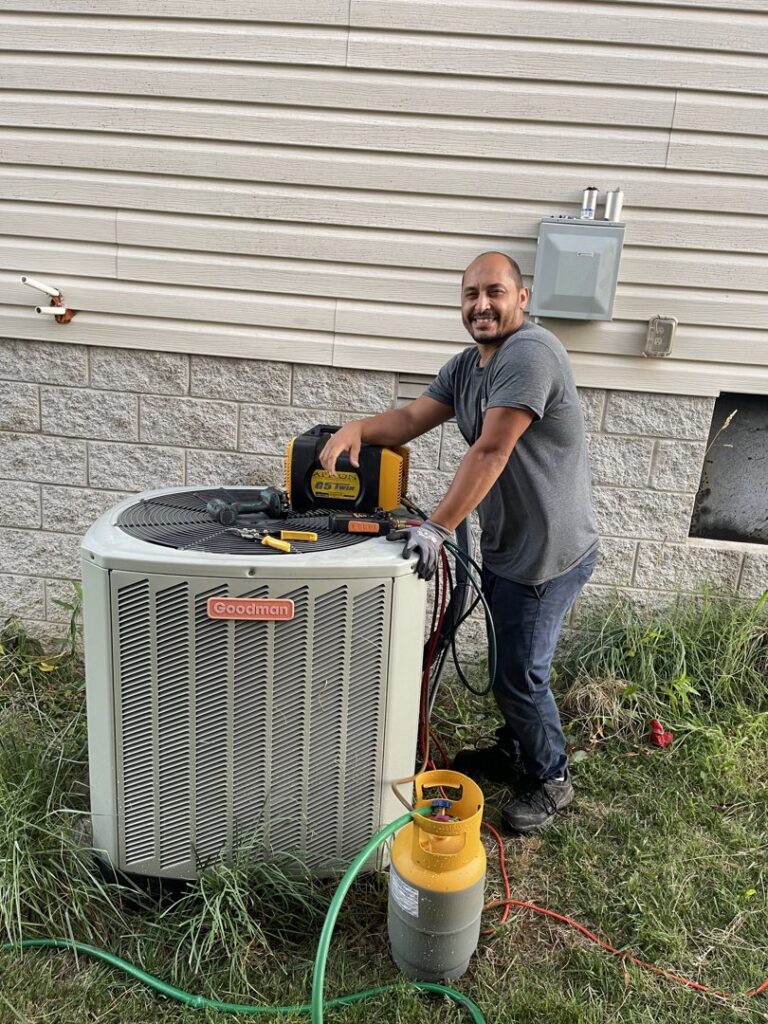 An HVAC technician from KMC Heating and Cooling LLC servicing a Goodman outdoor AC unit in Clarksville, TN.