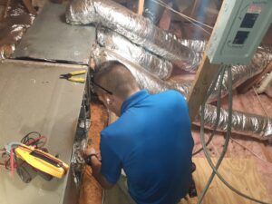 An HVAC technician servicing an indoor air handler or furnace unit in an attic for Calloway & Sons A/C And Heating in New Orleans, LA.