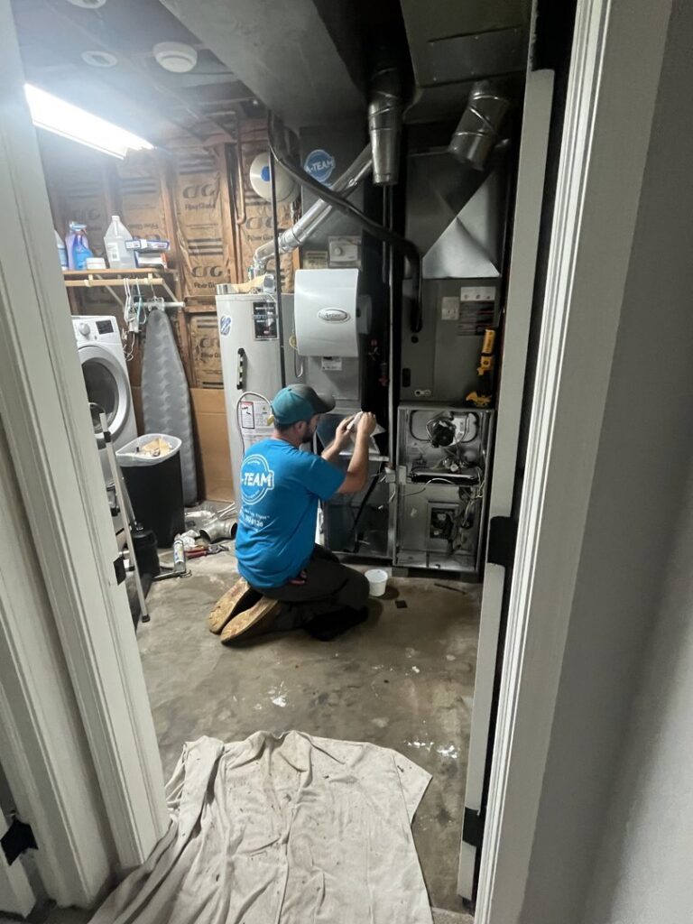 An A-Team PHC technician servicing an indoor furnace and air handler unit in Olathe, KS.