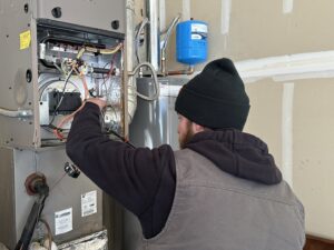 An HVAC technician servicing an indoor furnace unit for Access Heating & Air Conditioning in Fredericksburg, VA