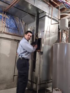 An HVAC technician from Neal Harris Service Experts servicing an indoor furnace or air handler unit in Overland Park, KS.
