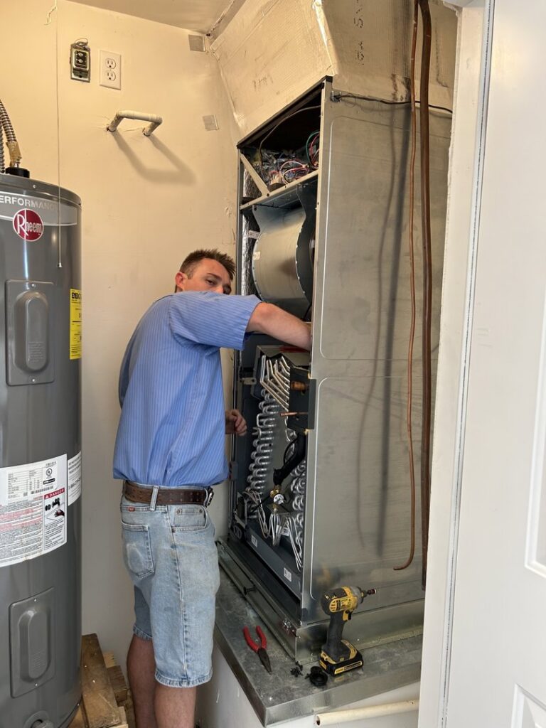 An HVAC technician servicing an indoor air handler unit for Advanced Comfort A/C & Heating in Phoenix, AZ.