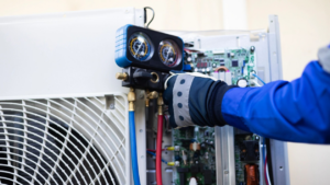 An HVAC technician servicing an indoor heating and cooling unit with gauges for Avery Heating and Cooling in Independence, MO.