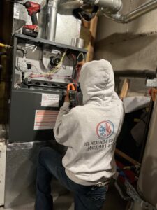 An HVAC technician from JCL Heating and Cooling LLC servicing an indoor furnace unit in Gresham, OR.