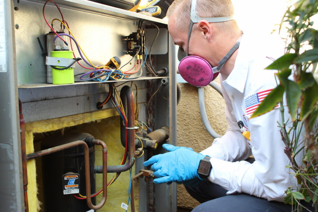 An HVAC technician servicing the internal components of an outdoor air conditioning unit for Controlled Climates Heating and Air Conditioning, Inc. in Fresno, CA.