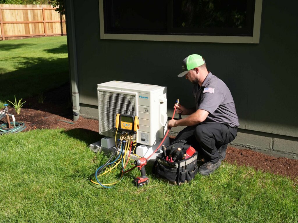 An Alpine Heating technician servicing a Daikin mini-split AC unit outdoors in Eugene, OR.
