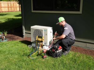 An Alpine Heating technician servicing a Daikin mini-split AC unit outdoors in Eugene, OR.