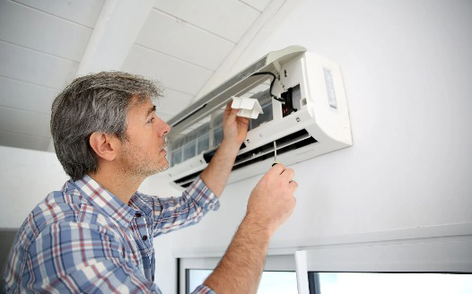 An HVAC technician servicing a mini-split air conditioning unit for Bellis Heating & Cooling in Independence, MO.