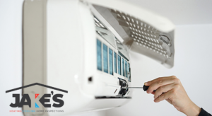 An HVAC technician servicing an indoor mini-split air conditioning unit for Jake's Heating and Cooling in Buffalo, NY.