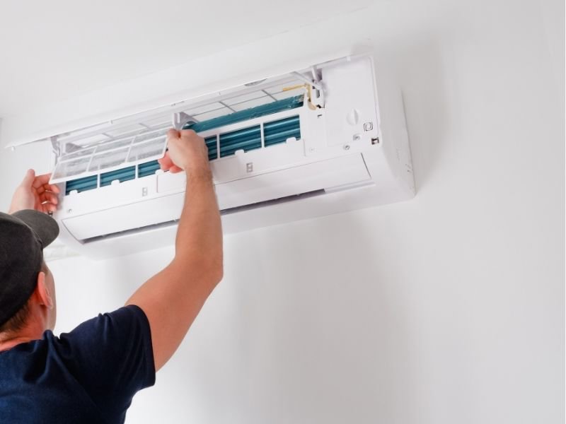 An HVAC technician servicing an indoor mini-split air conditioning unit for Trinity Heating and Air in Anaheim, CA