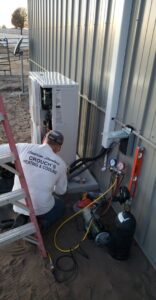 An HVAC technician from Crouch's Heating & Cooling LLC servicing an outdoor mini-split condenser unit in Stillwater, OK.