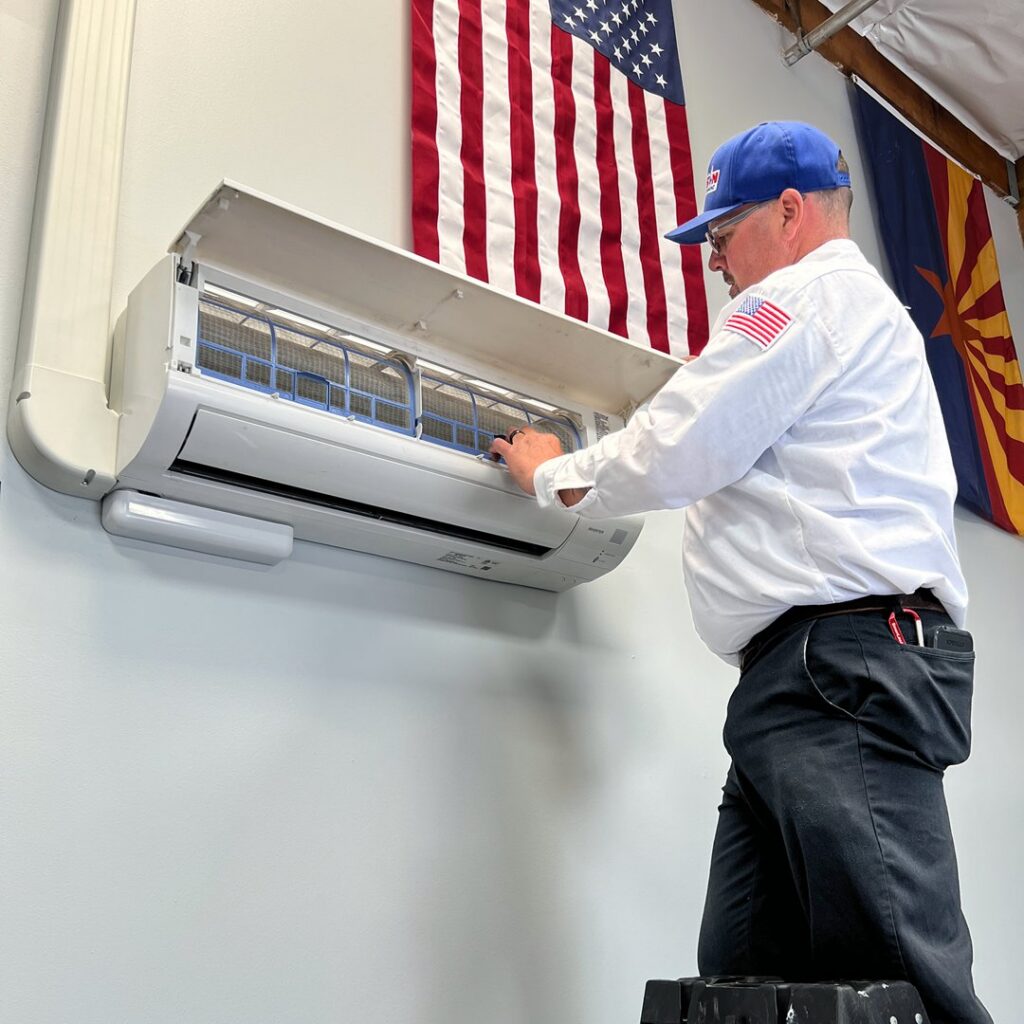 An HVAC technician servicing an indoor mini-split unit for Larson Air Conditioning in Scottsdale, AZ