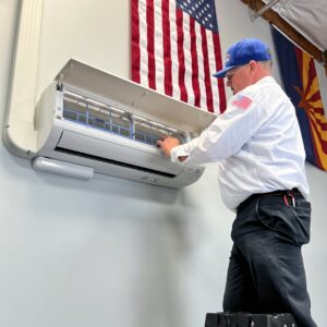 An HVAC technician servicing an indoor mini-split unit for Larson Air Conditioning in Scottsdale, AZ