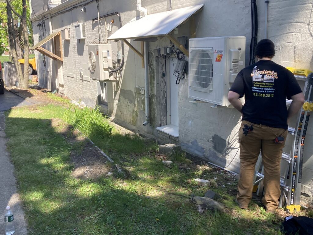 An HVAC technician from Freedom Air Mechanical Contractors LLC servicing a Mitsubishi Electric mini-split unit in Everett, MA.