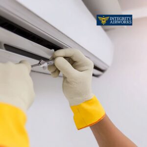 An HVAC technician in gloves servicing an indoor mini-split air conditioning unit for Integrity Airworks in Hoover, AL.