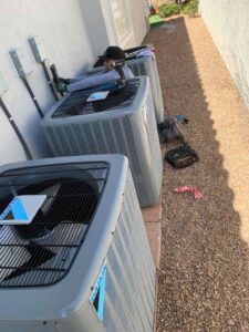 An Instant Air HVAC technician servicing multiple outdoor condenser units in Las Vegas, NV.