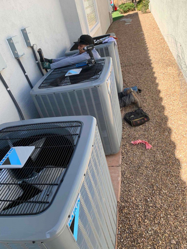 An Instant Air HVAC technician servicing multiple outdoor condenser units in Las Vegas, NV.