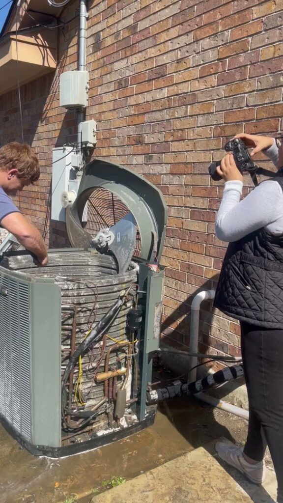 An HVAC technician servicing an open outdoor AC unit for Airtegrity Comfort Solutions in San Antonio, TX