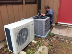 An Action Mechanical LLC technician servicing an outdoor air conditioning unit and a mini-split unit in Eau Claire, WI.