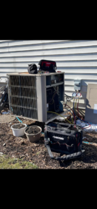 An HVAC technician servicing an outdoor air conditioning unit with tools and gauges, demonstrating work by ACW Heating & Air in North Aurora, IL