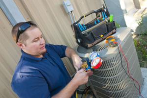 An HVAC technician servicing an outdoor air conditioning unit with gauges and tools for APM Heating and Air Conditioning in Columbia, MO.