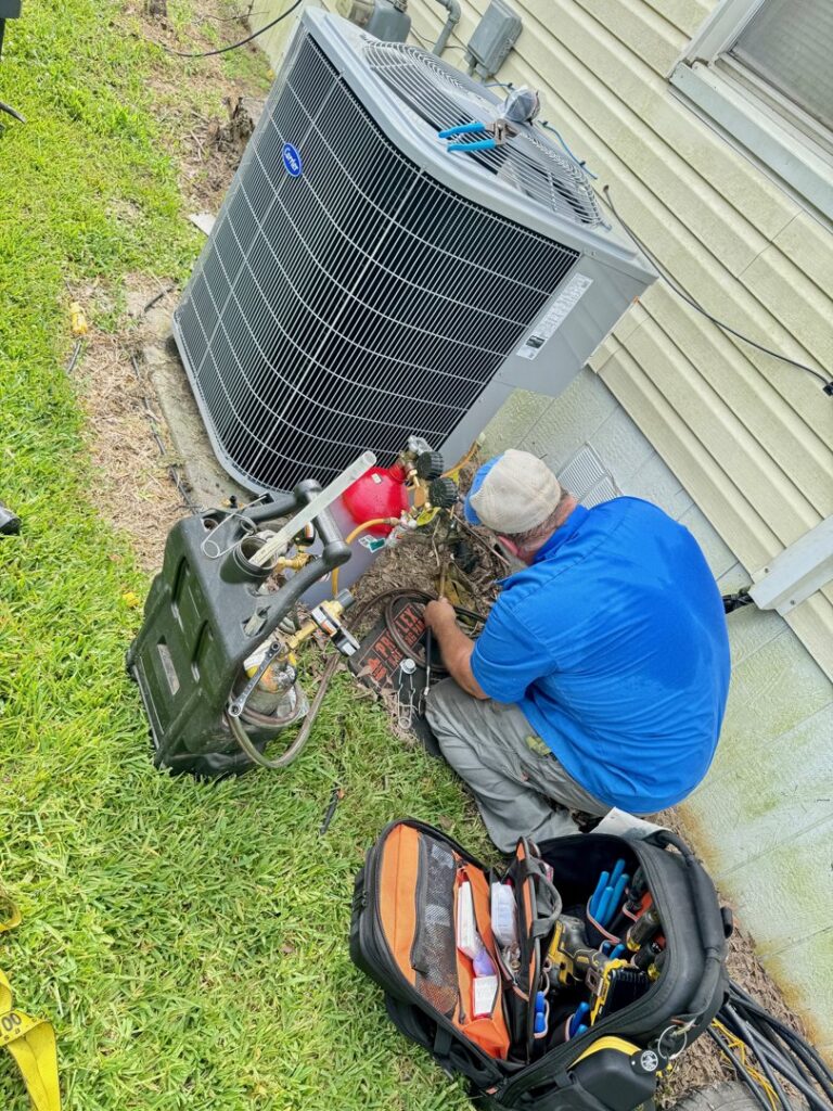 An ARKLA AIR LLC technician servicing an outdoor air conditioning unit with tools and gauges in Springhill, LA.