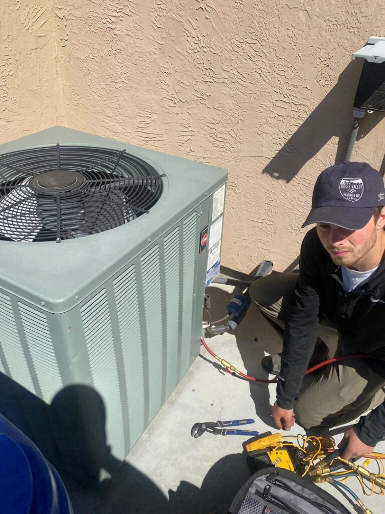 An HVAC technician servicing an outdoor air conditioning unit with tools at a job site for Boise Valley Heating & Air in Meridian, ID