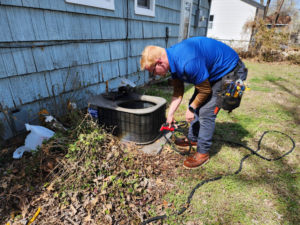 An HVAC technician servicing an outdoor air conditioning unit at Bowers Heating and Air Conditioning in Wichita, KS