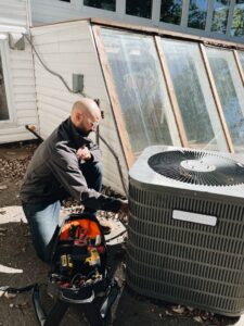 A professional HVAC technician from Davis Heating, Air Conditioning & Home servicing an outdoor air conditioning unit in Overland Park, KS.