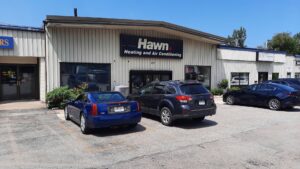 An HVAC technician performing maintenance or repair on an outdoor air conditioning unit for Hawn Heating and Air Conditioning in Rochester, NY.