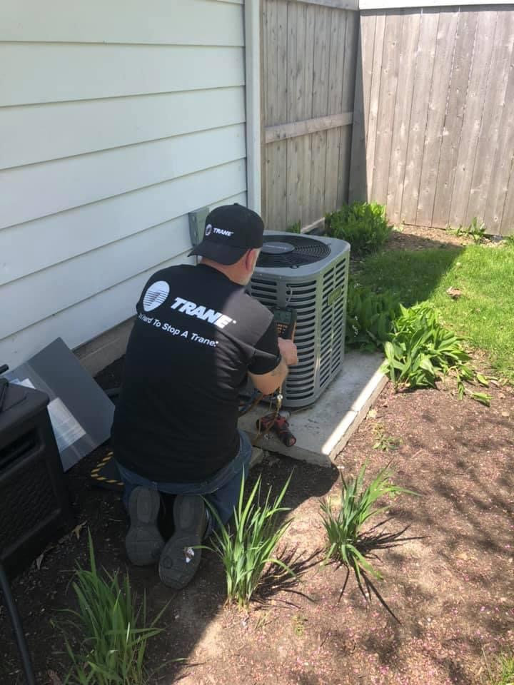 An HVAC technician servicing an outdoor air conditioning unit for Nortek Environmental, Inc. in Naperville, IL.