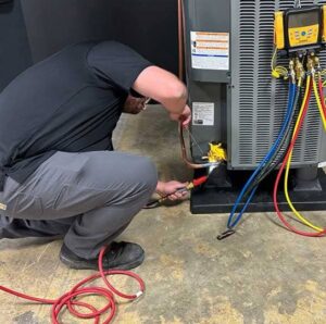 An HVAC technician connecting service hoses to an outdoor air conditioning unit during a maintenance call by Prime Home HVAC in York, PA.