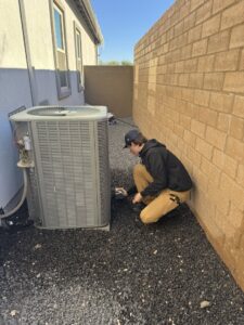 An HVAC technician from Rusty's Air Conditioning And Heating servicing an outdoor AC unit in Mesa, AZ.