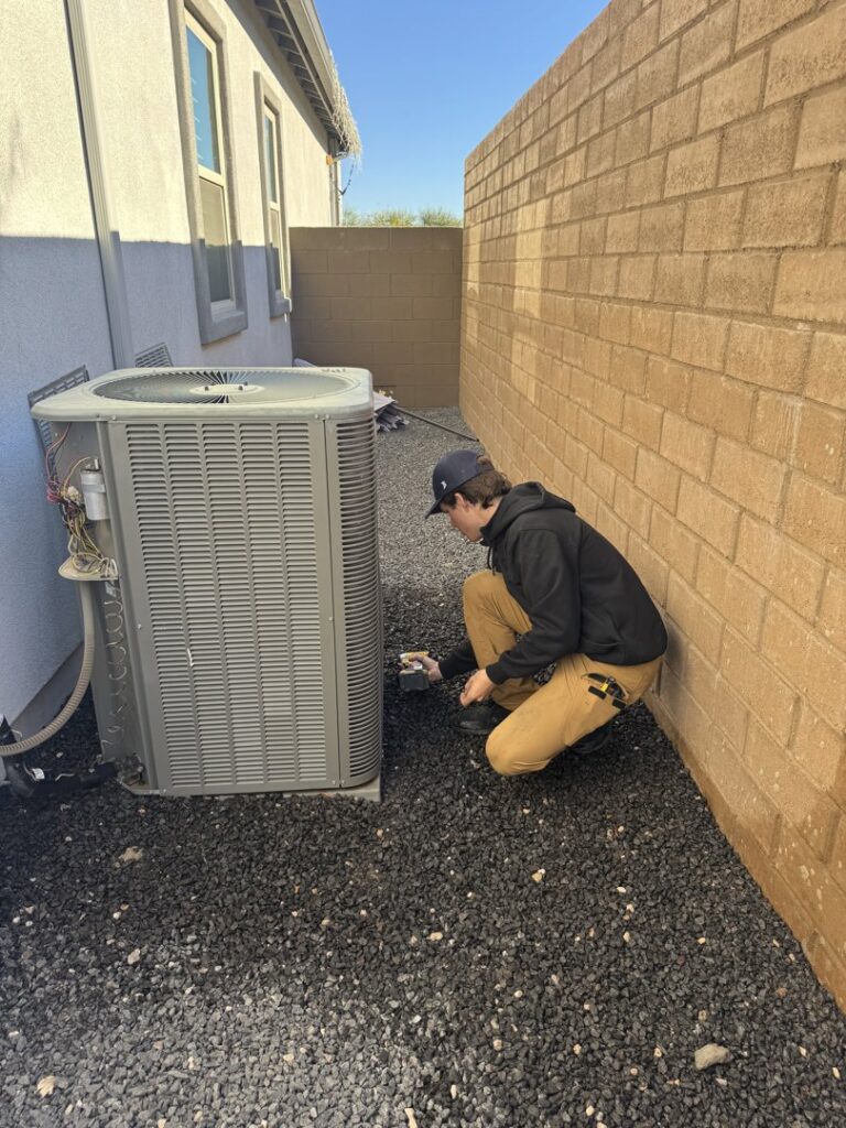 An HVAC technician from Rusty's Air Conditioning And Heating servicing an outdoor AC unit in Mesa, AZ.