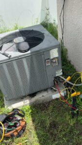An HVAC technician servicing an outdoor AC unit with gauges connected for Timely Air Conditioning in Riverview, FL.