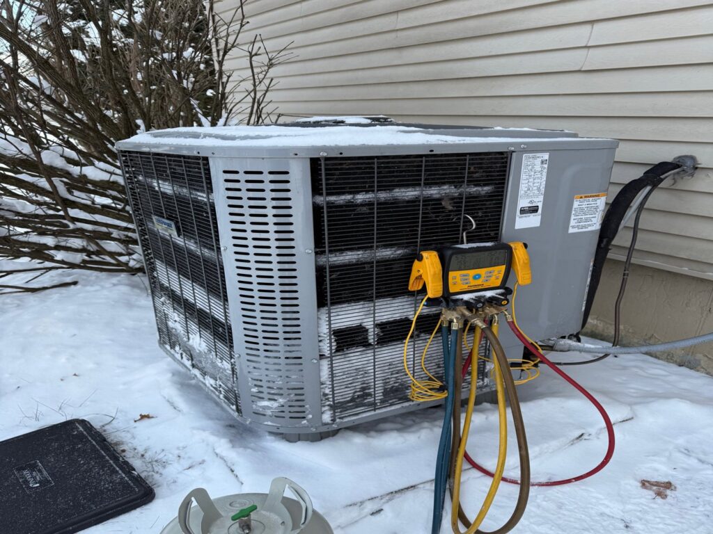 An HVAC technician servicing an outdoor AC unit in winter for Zongora Comfort Solutions LLC in Allentown, PA.