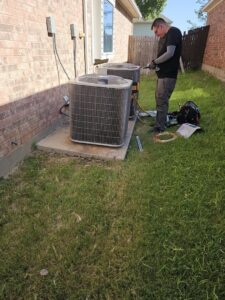 An HVAC technician servicing two outdoor AC units with tools and copper tubing for MasterCraft Mechanical, LLC. in Haslet, TX.