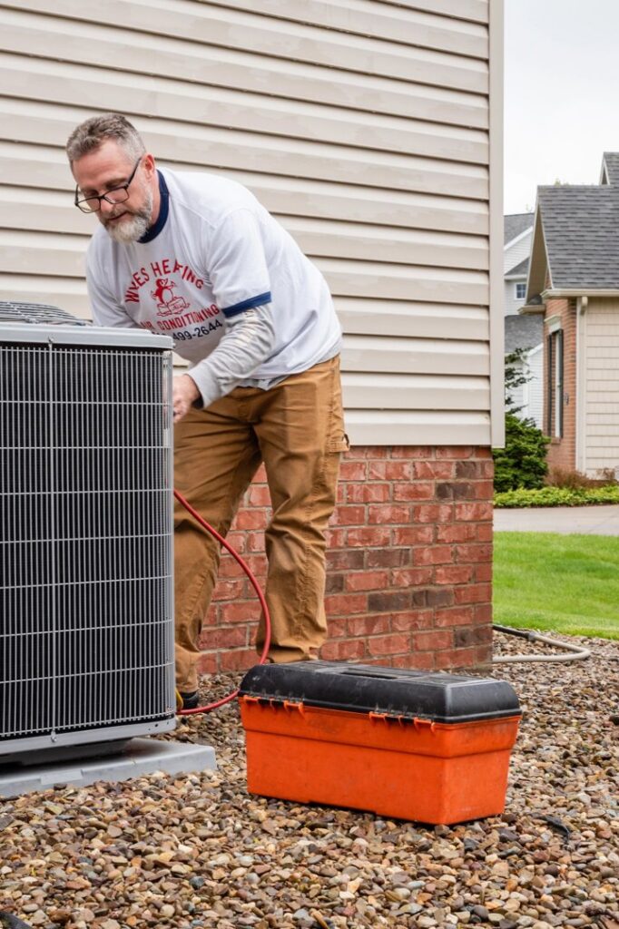 An HVAC technician from Wyles Heating & Air Conditioning Inc. servicing an outdoor air conditioning unit in North Canton, OH.