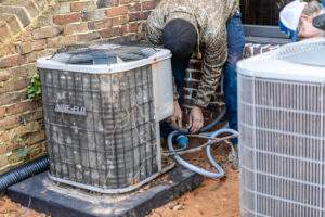 An HVAC technician servicing an outdoor air conditioning condenser unit for Comfort Engineering Co Inc in Tupelo, MS