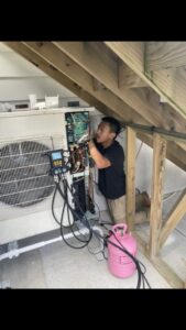 An HVAC technician from Freedom Air Mechanical Contractors LLC servicing an outdoor mini-split unit with gauges in Everett, MA.