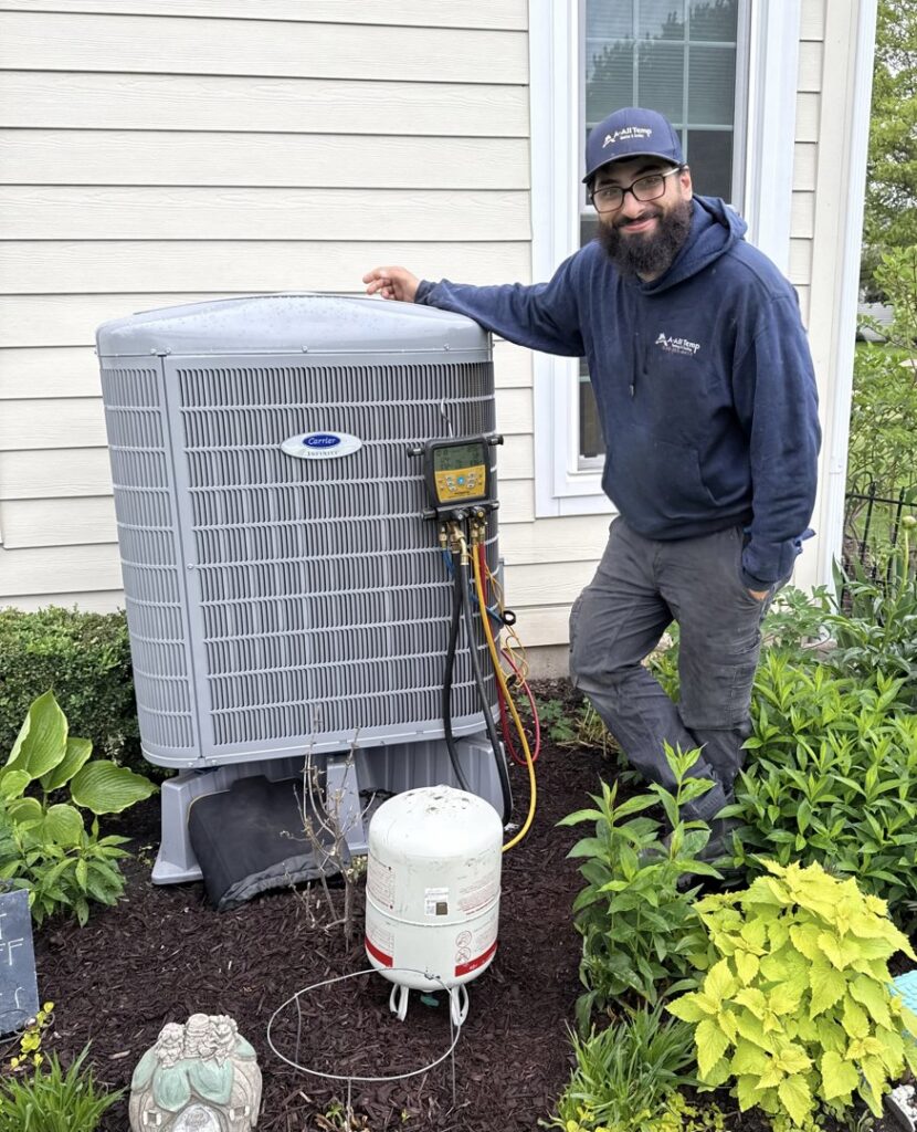 An HVAC technician from A All Temp Inc. Heating & Cooling servicing an outdoor unit in Naperville, IL.