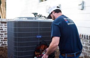 An Air Control Heating and Cooling technician servicing an outdoor HVAC unit at a residential property in Tallahassee, FL.
