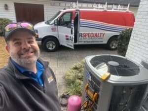 An Air Specialty Heating & Air Conditioning technician servicing an outdoor HVAC condenser unit in Norfolk, VA.