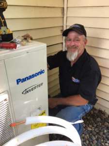 An HVAC technician servicing an outdoor Panasonic Inverter unit for Automatic Heating And Air Inc. in Fargo, ND
