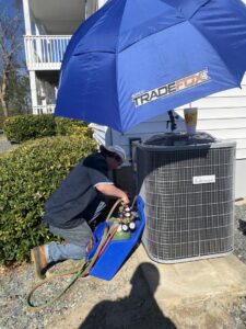 An HVAC technician from Brand Air Heating and Cooling LLC servicing an outdoor AC unit in Wilmington, NC.