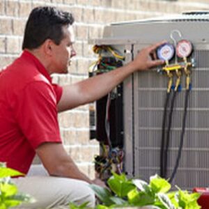 An HVAC technician servicing an outdoor condenser unit with gauges for Dan Deckard Hvac in Charlotte, NC