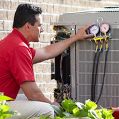 An HVAC technician servicing an outdoor condenser unit with gauges for Dan Deckard Hvac in Charlotte, NC