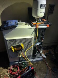 An HVAC technician from Fuse HVAC & Appliance Repair Boston servicing an outdoor unit with gauges in West Roxbury, MA.