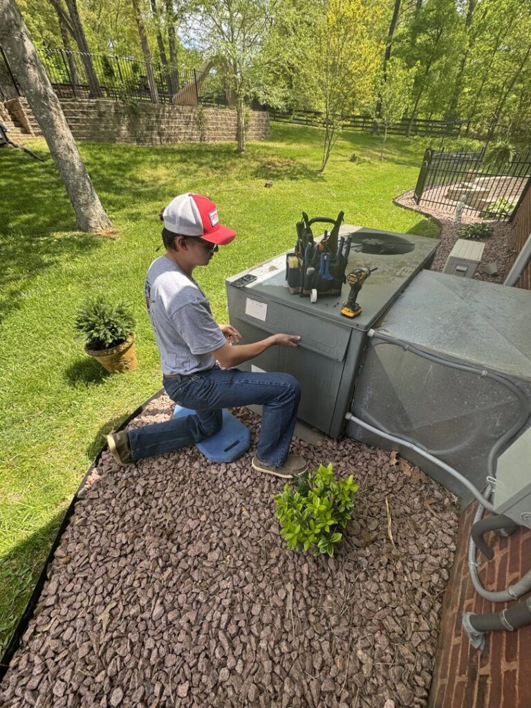An HVAC technician servicing an outdoor air conditioning unit for Grace Heating & Air in Clarksville, TN.